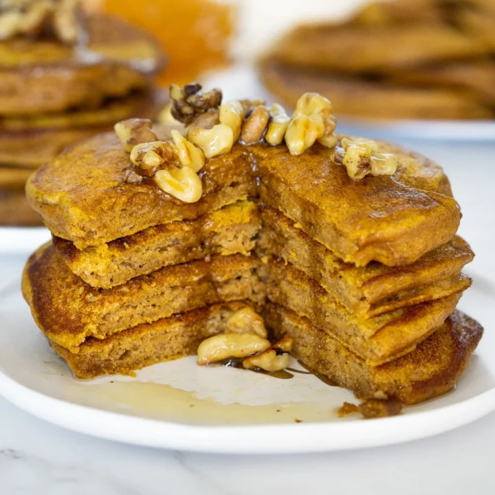 cut stack of protein pancakes with walnuts and syrup.