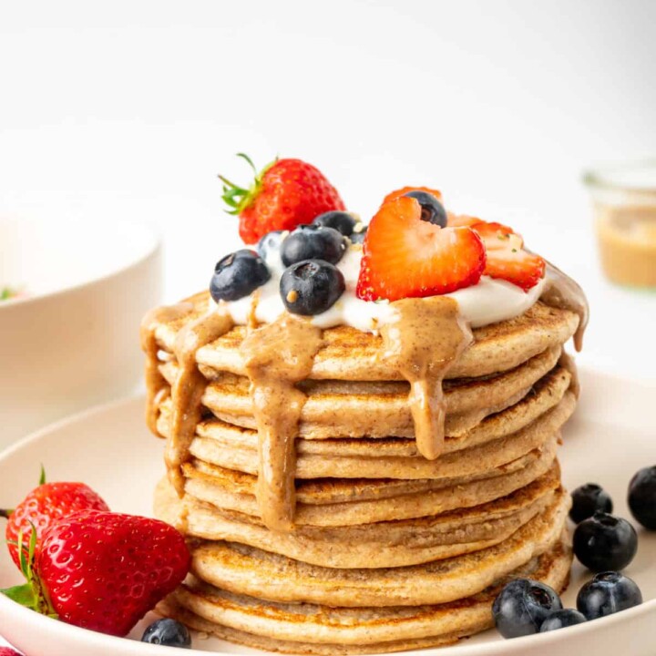 stack of protein pancakes topped with nut butter and berries.