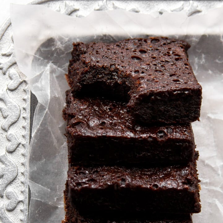 collagen protein brownies layered on a plate, one bitten.