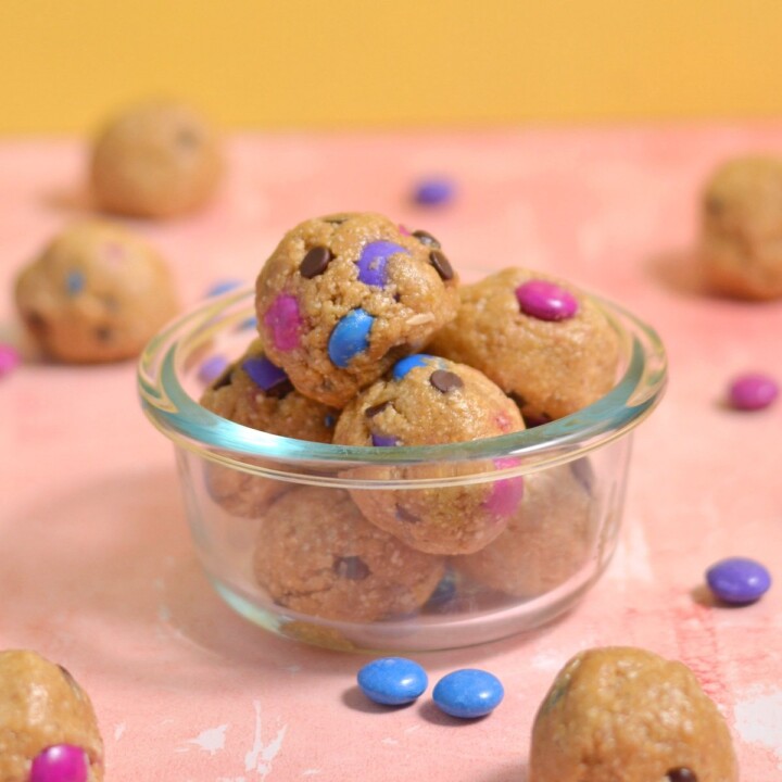 protein balls with colored candy coated chocolate pieces and chocolate chips, in a small glass dish.