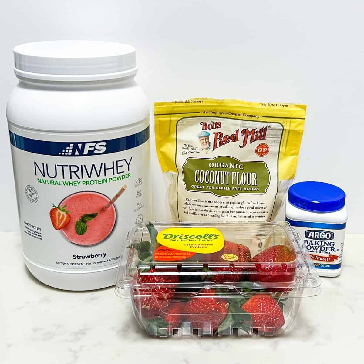 ingredients for strawberry protein cookies - strawberry whey protein powder, coconut flour, baking powder, and fresh strawberries.