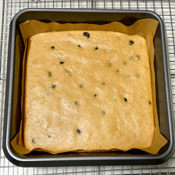 baked chocolate chip protein blondies in a parchment-lined pan on a wire cooling rack.