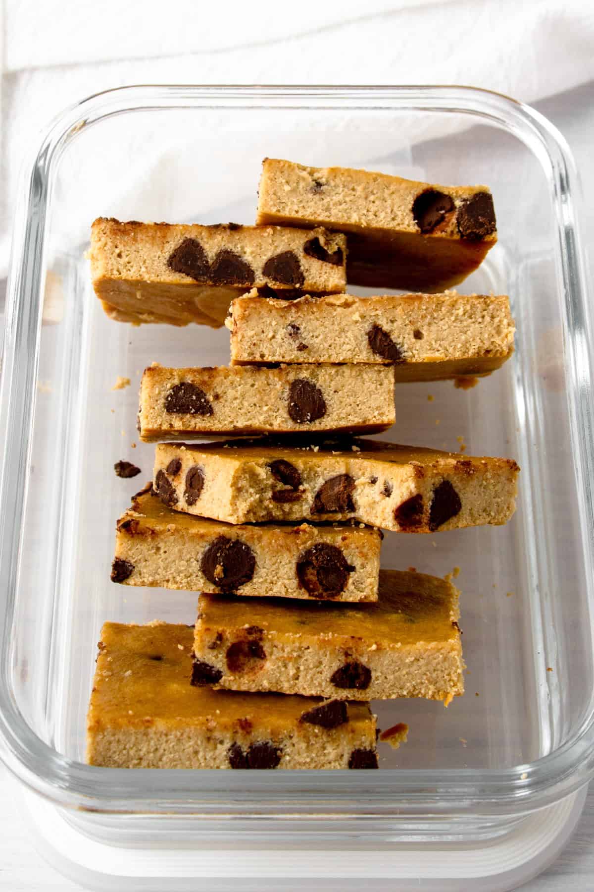 chocolate chip protein blondies, one bitten, in a glass meal prep container.