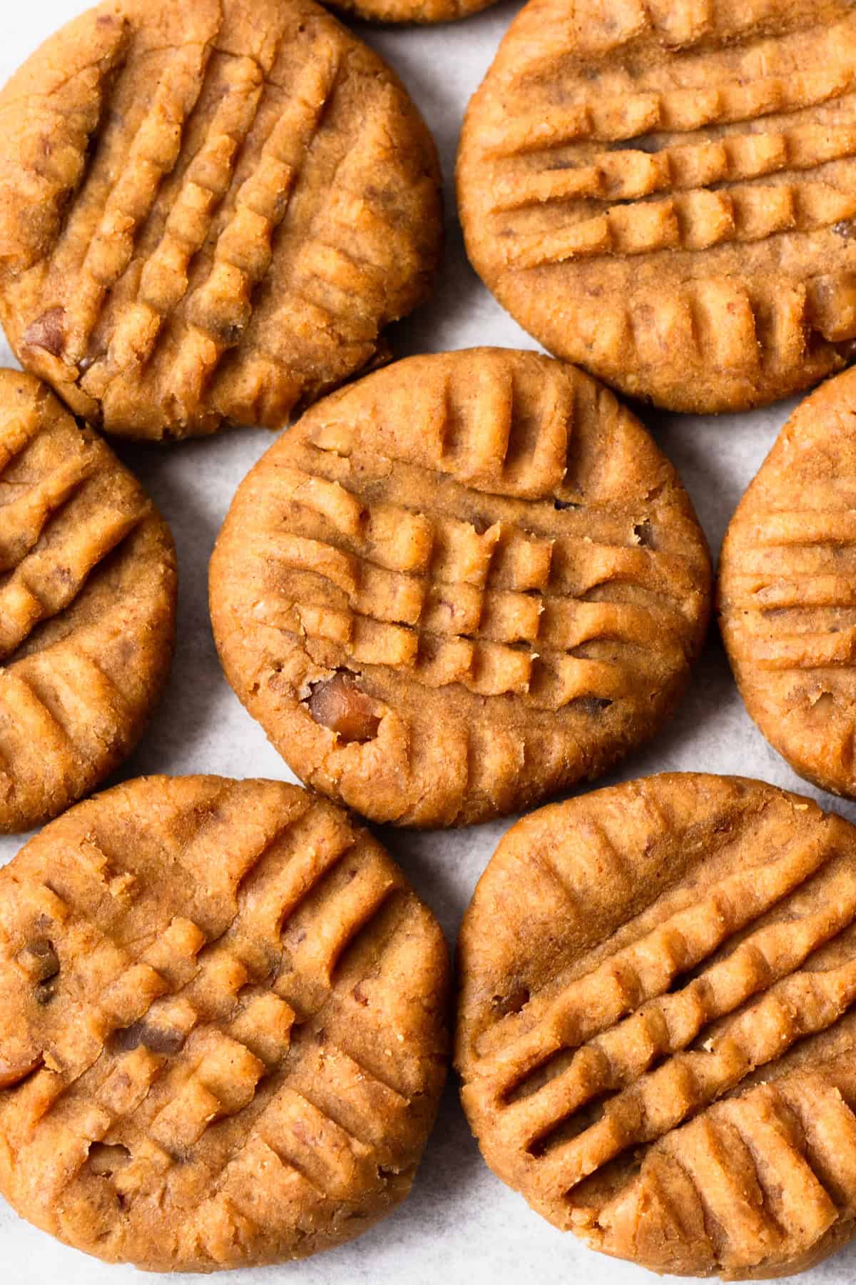 several peanut butter protein cookies touching on a flat surface.