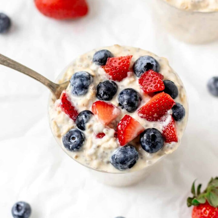 bowl of overnight oats with berries, surrounded by extra berries.