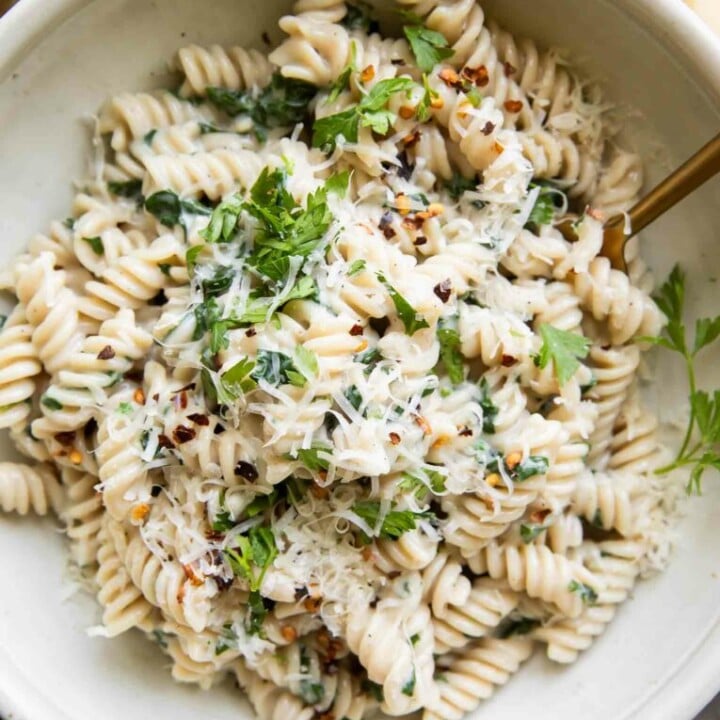 bowl of spiral pasta with cheese and parsley.
