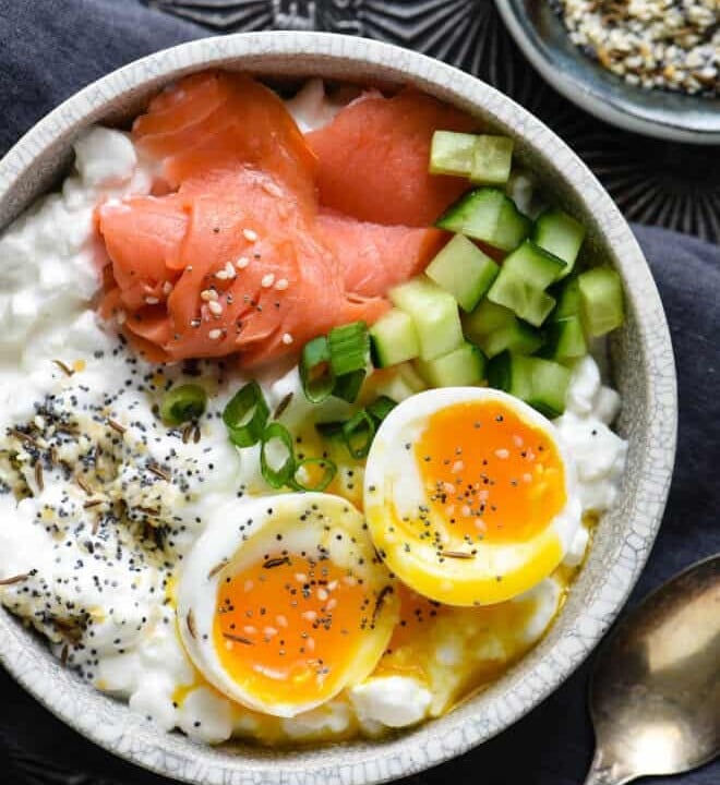 breakfast bowl with lox, boiled egg, cottage cheese, cucumber, and scallions.