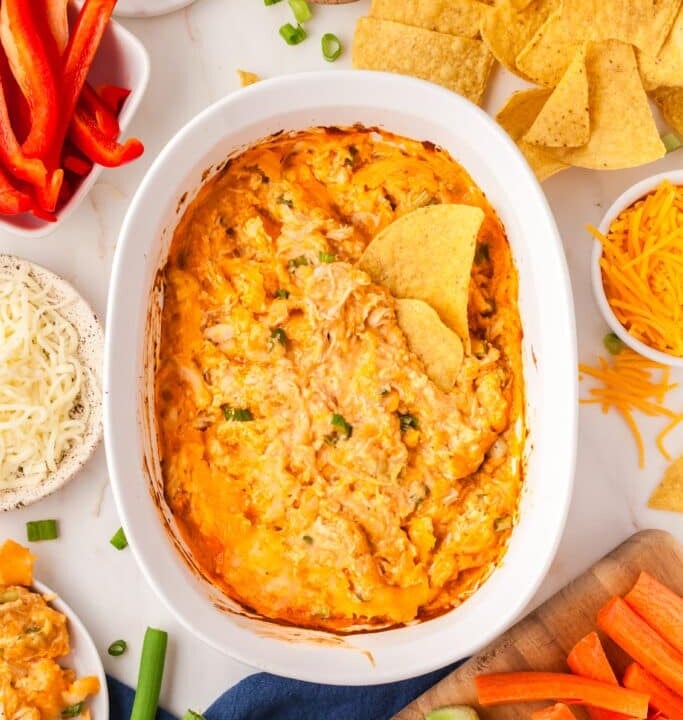 bowl of buffalo chicken dip surrounded by chips and vegetables.