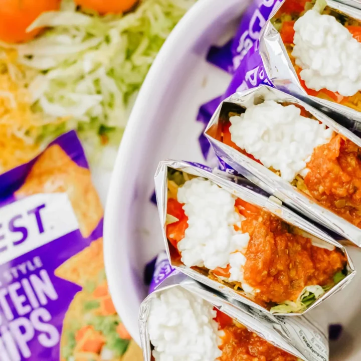several walking tacos (made in a bags of chips) in a serving dish.