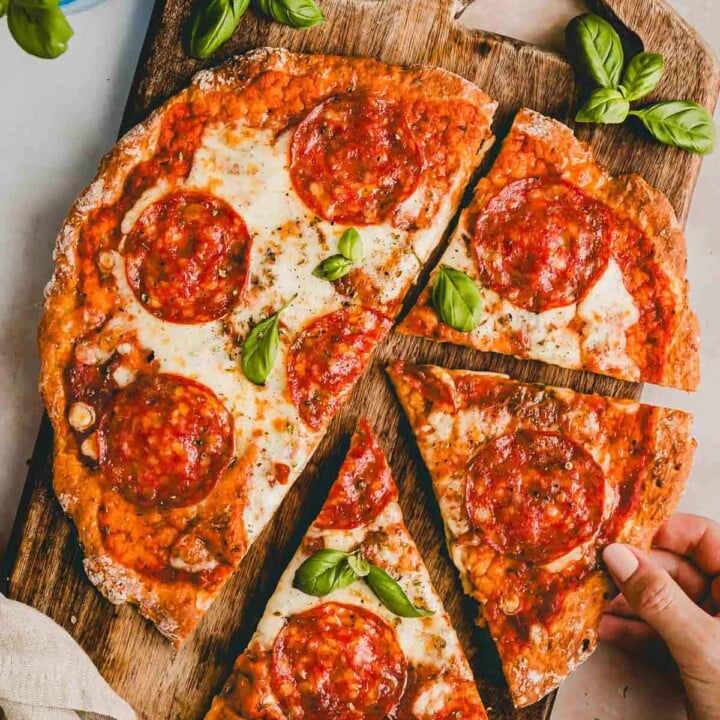 small pepperoni pizza with a piece being pulled away.