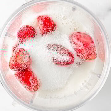 frozen strawberries, almond milk, and sweetener in a blender cup.