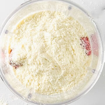 frozen strawberries, almond milk, sweetener, and protein powder in a blender cup.
