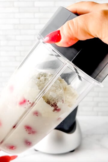 blender cap being put on the blender cup, ready to blend the strawberry protein shake.