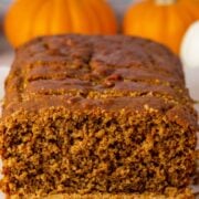 sliced loaf of high protein pumpkin bread on a cutting board surrounded by decorative mini pumpkins, with text overlay.