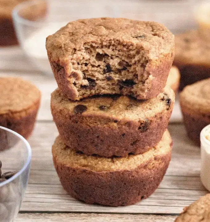 protein chocolate chip muffins stacked on a wood surface.