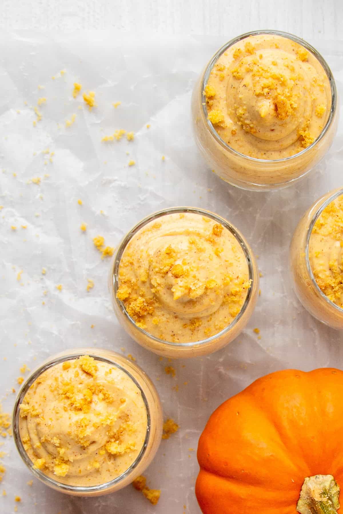 top view of 4 servings of pumpkin cheesecake mousse with a decorative mini pumpkin.