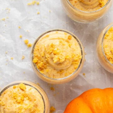 top view of 4 servings of pumpkin cheesecake mousse with a decorative mini pumpkin.