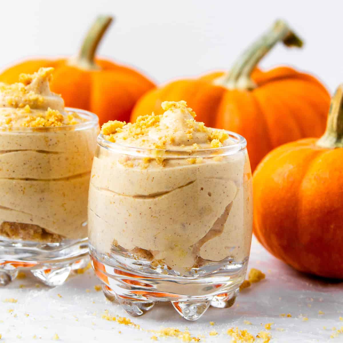 2 servings of pumpkin cheesecake mousse with decorative mini pumpkins.