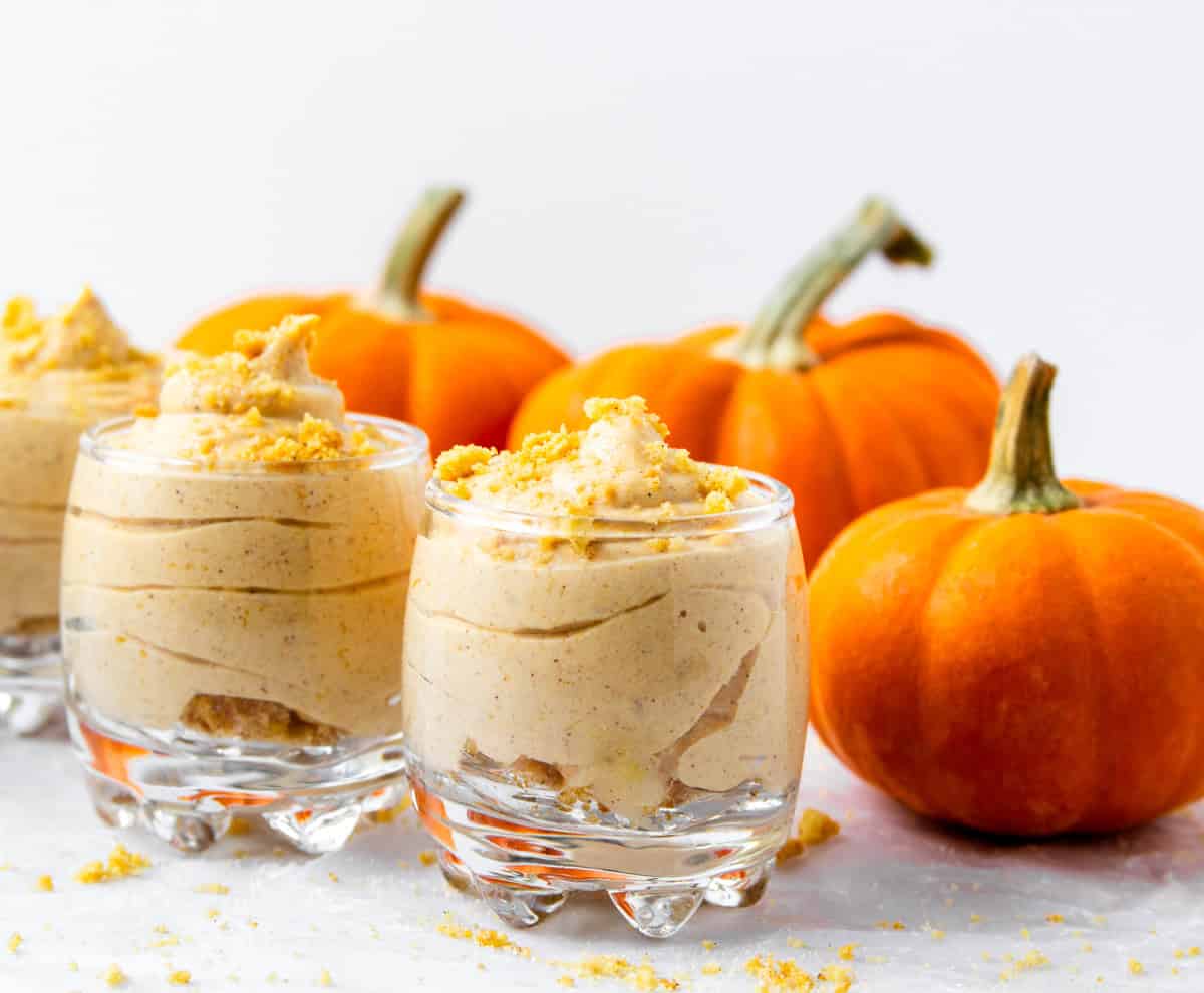 3 servings of pumpkin cheesecake mousse with decorative mini pumpkins.