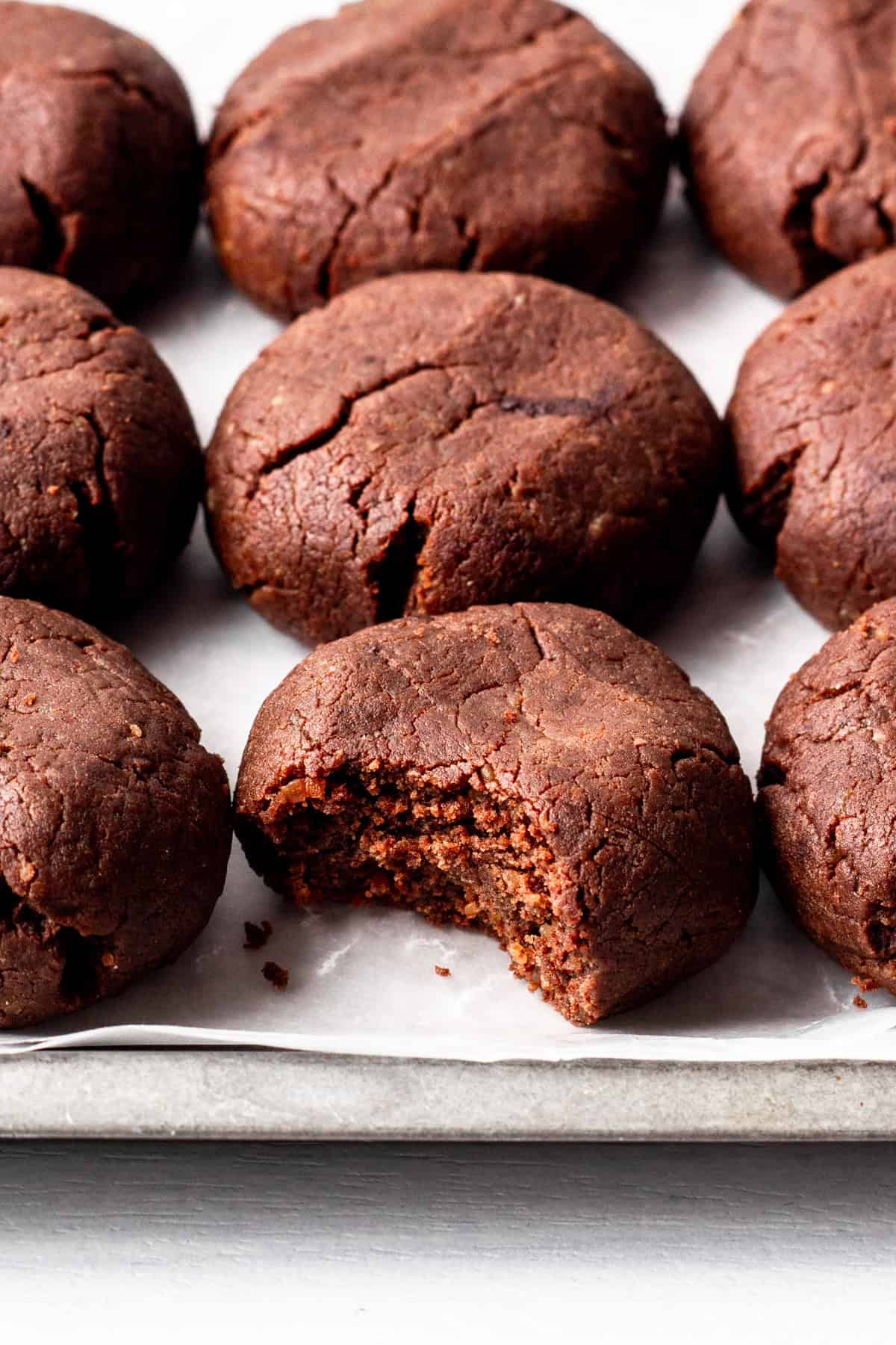 chewy chocolate protein cookies on a tray, one bitten.
