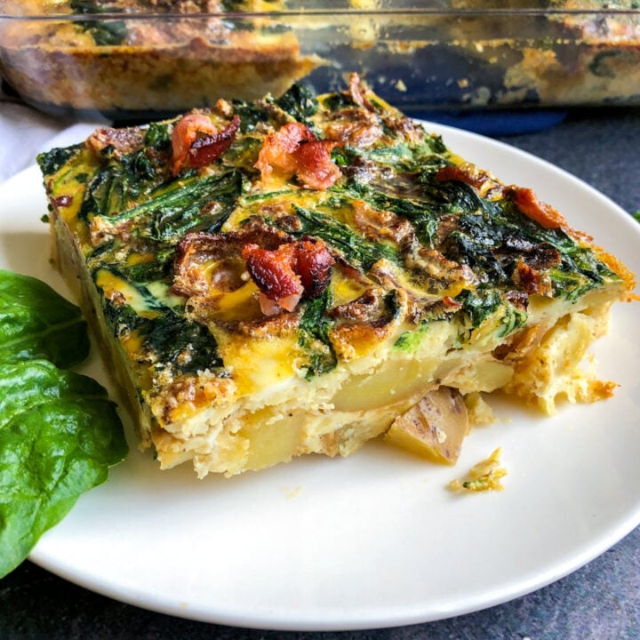 a square piece of bacon spinach potato egg casserole on a plate.