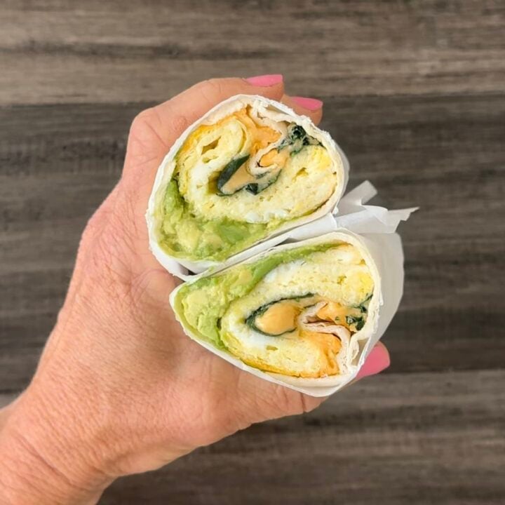 hand holding two halves of breakfast wrap.