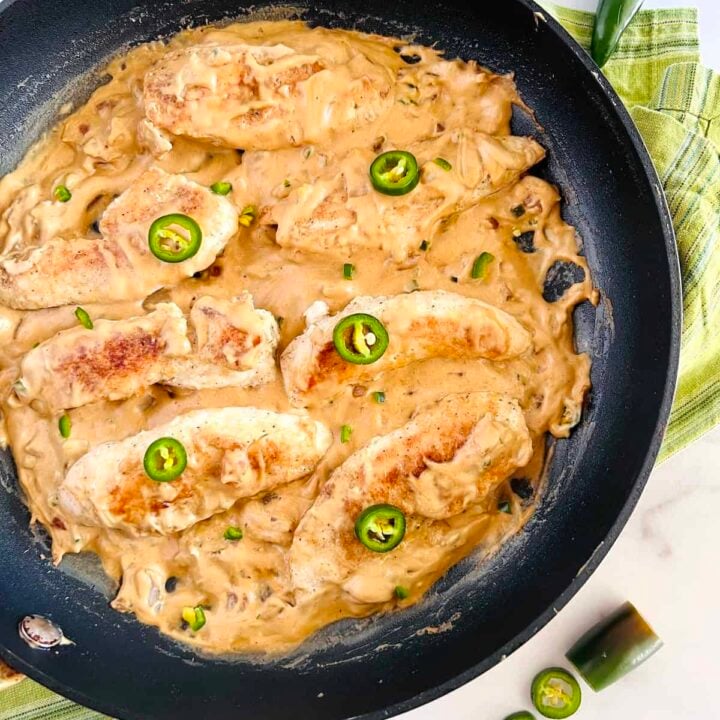 top view of a chicken tenders with a cheesy jalapeรฑo sauce in a skillet.