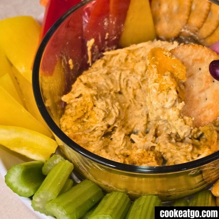 cracker dipping into chicken buffalo dip.