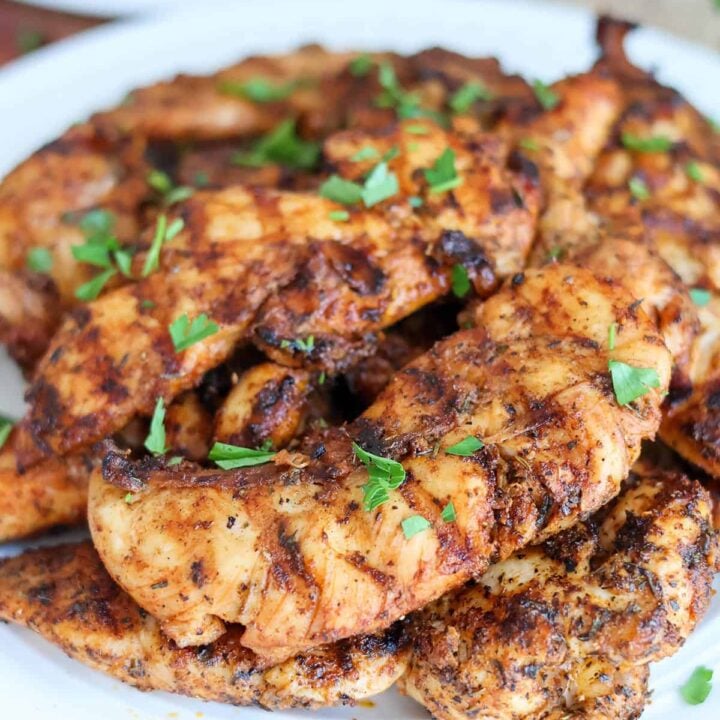pile of grilled chicken tenders with garnish.
