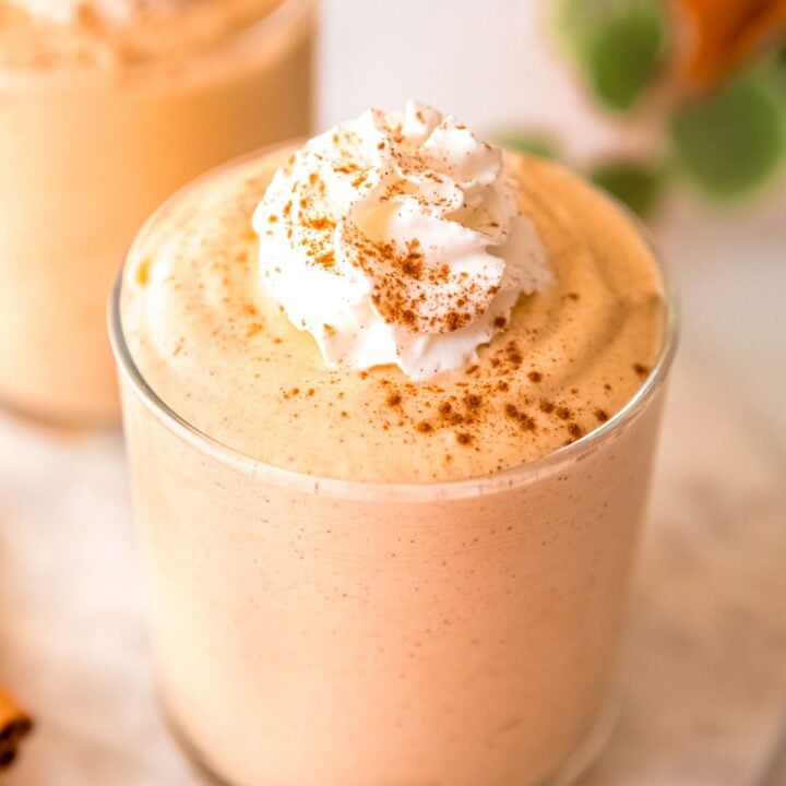 pumpkin protein fluff topped with whipped cream and cinnamon in a glass serving dish.