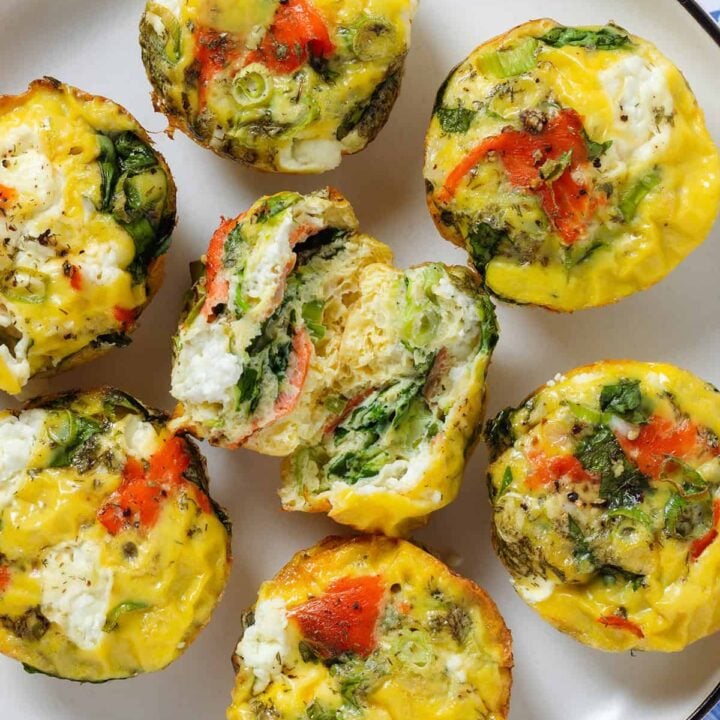several egg muffins with salmon on a plate, one cut open.