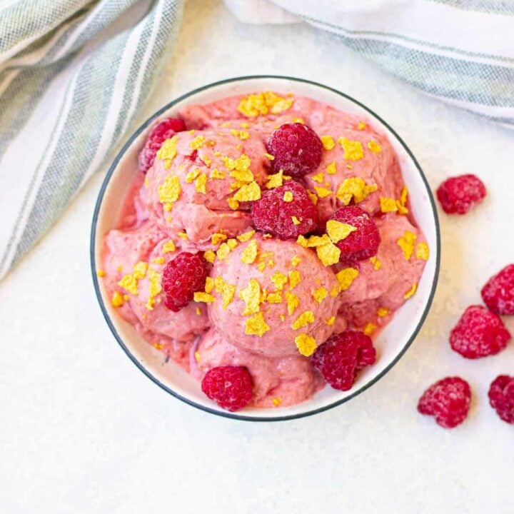 Delicious raspberry protein ice cream with yellow topping and fresh berries, perfect for healthy dessert options.