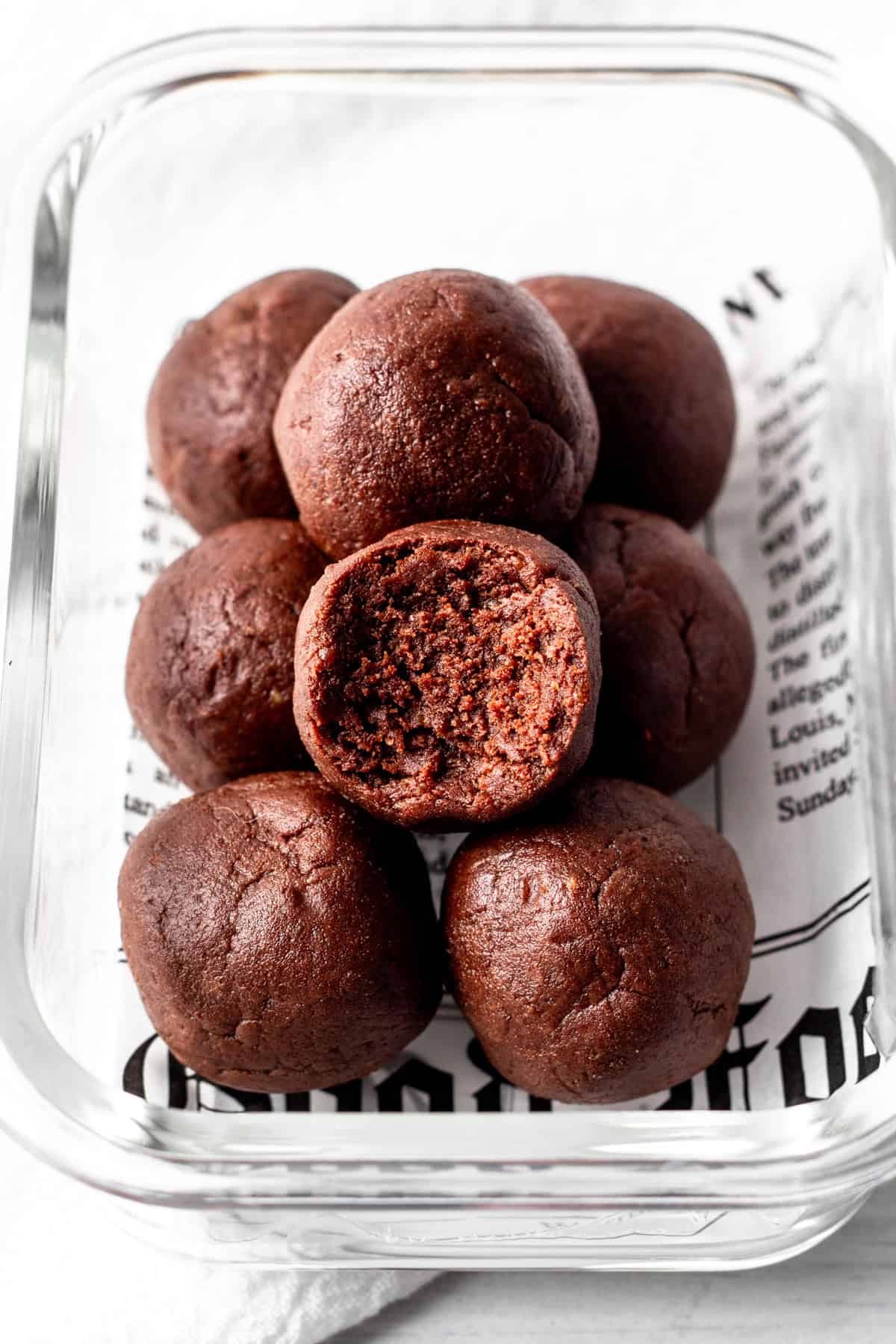 chocolate protein balls in a meal prep container with one bitten.