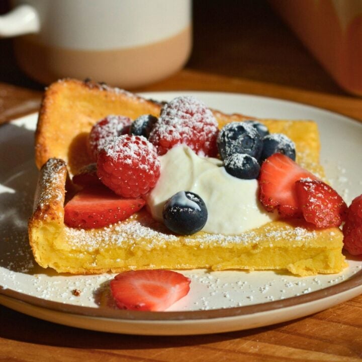 square piece of german pancake topped with fresh berries.