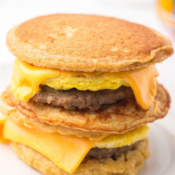sandwich stack of pancakes, sausage patties, egg patties, and melted cheese squares.