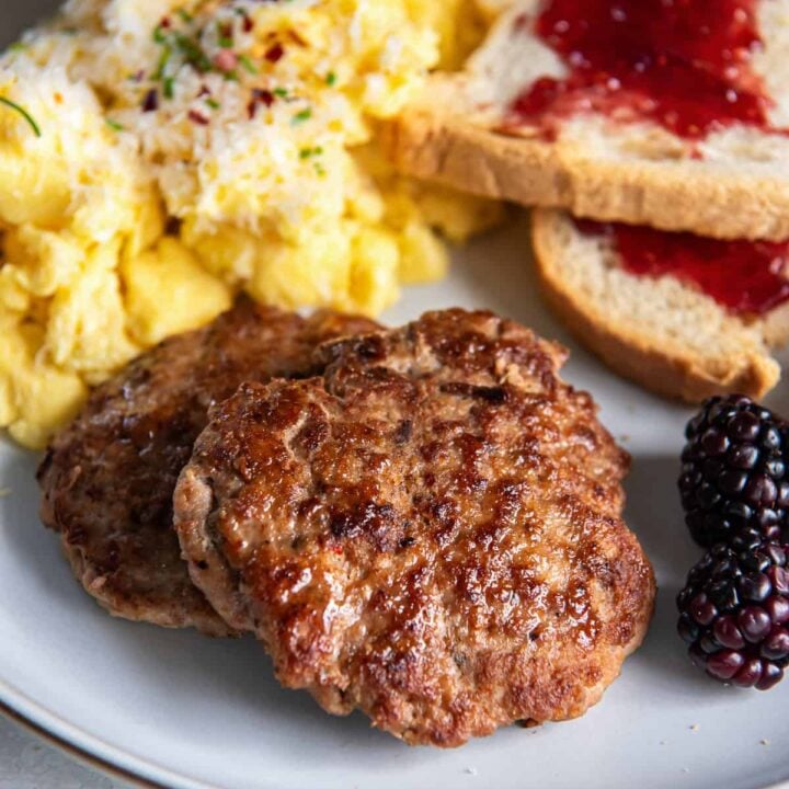 two turkey breakfast sausage patties with scrambled eggs and toast.