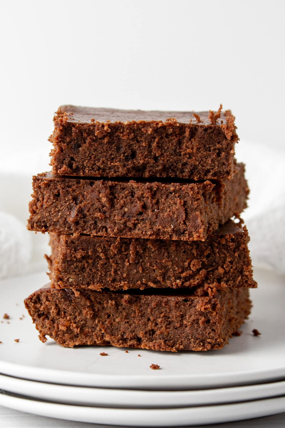 stacked whey protein brownies on a stack of plates.
