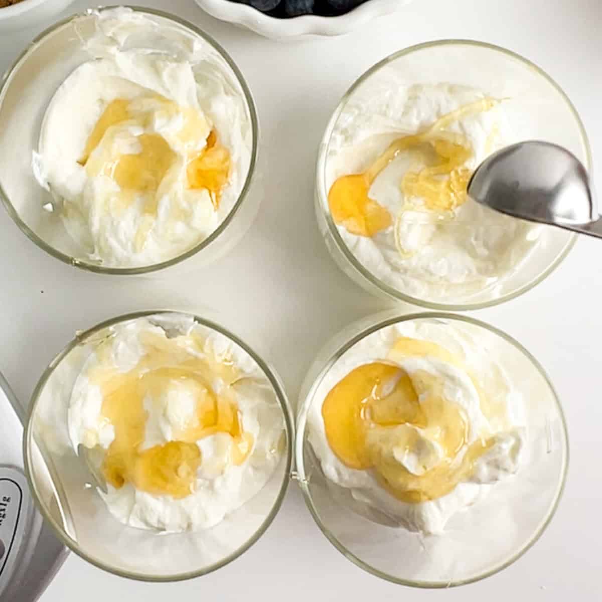 honey drizzled on yogurt in four jars.