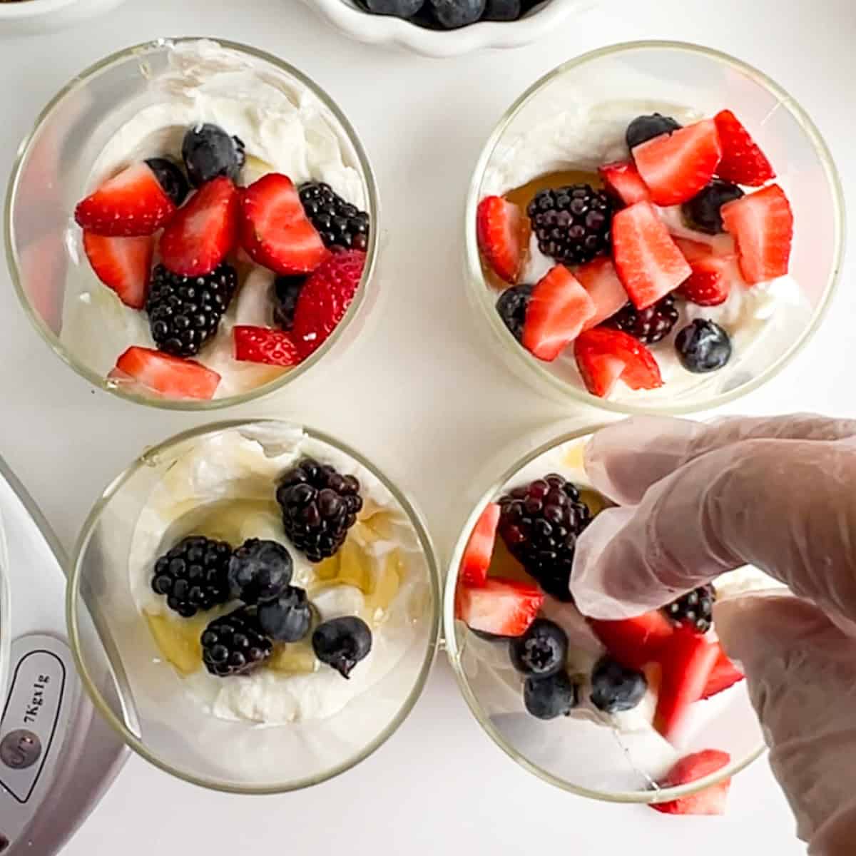 strawberries, blueberries, and blackberries on yogurt and honey in jars.