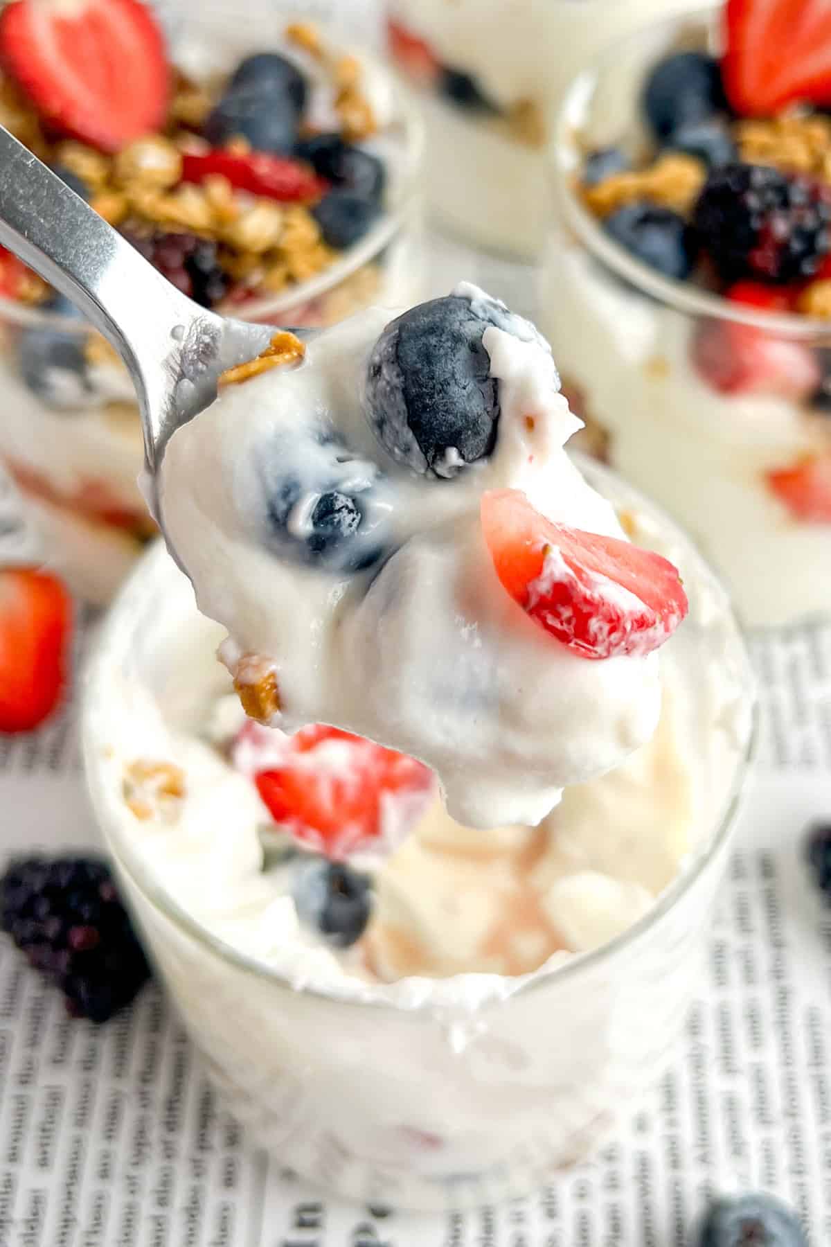 jar of high protein yogurt parfait with Greek yogurt, blueberries, strawberries, blackberries, granola, and honey.