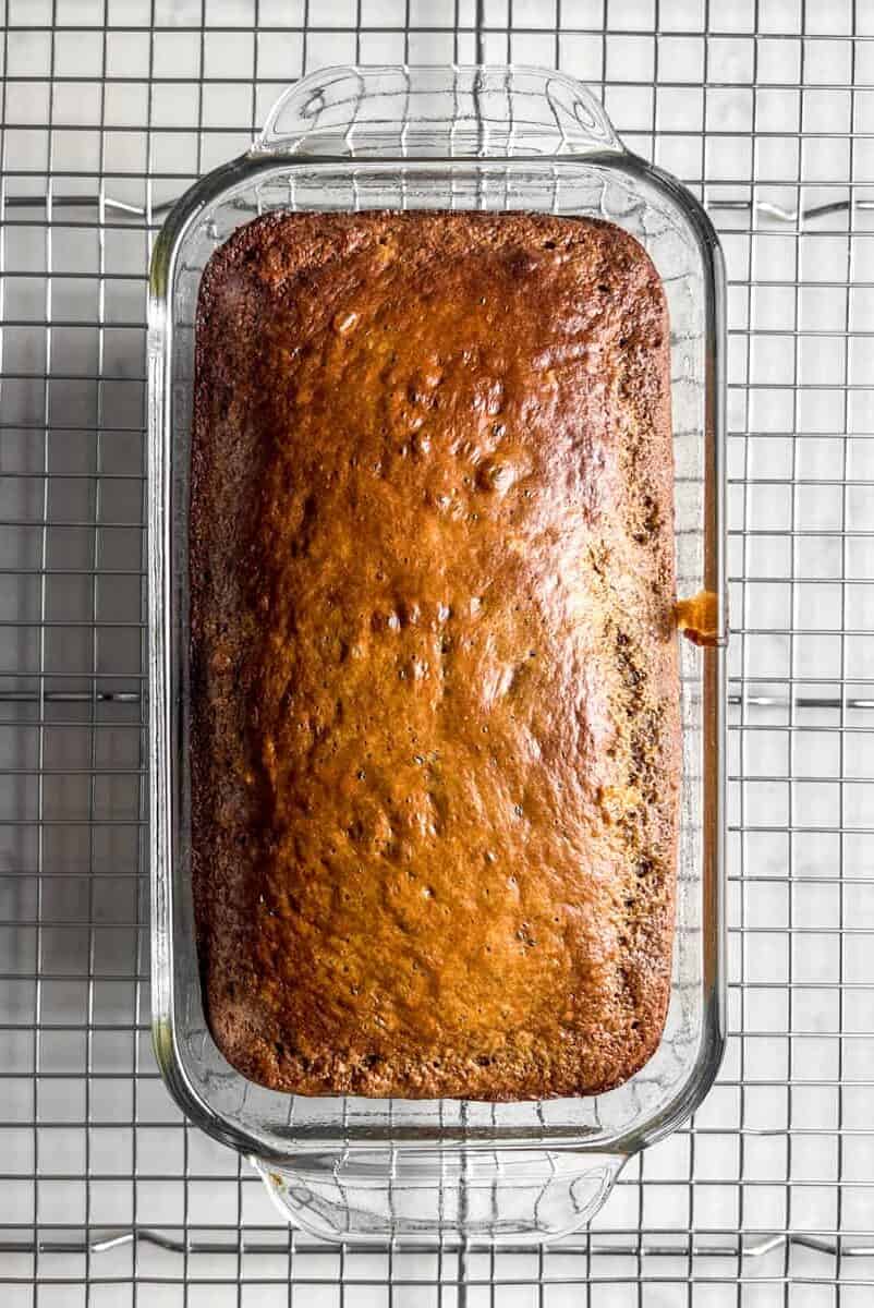 top view of a loaf of protein banana bread in a glass baking pan on a wire cooling rack.